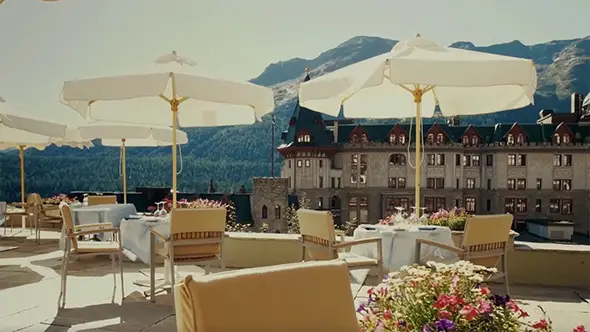 Летняя терраса ресторана La Diala в отеле Badrutt&rsquo;s Palace с видом на историческое здание и горы.