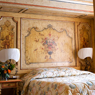 Элегантная спальня пентхауса La Loze в Куршевеле 1850: винтажная фреска с цветочным орнаментом над кроватью, классические лампы и покрывало в пастельных тонах.