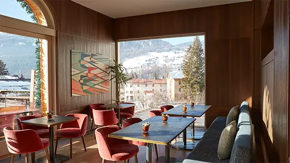 Интерьер элегантного ресторана в Grand Hotel Savoia в Кортине с большими окнами и видом на Альпы.