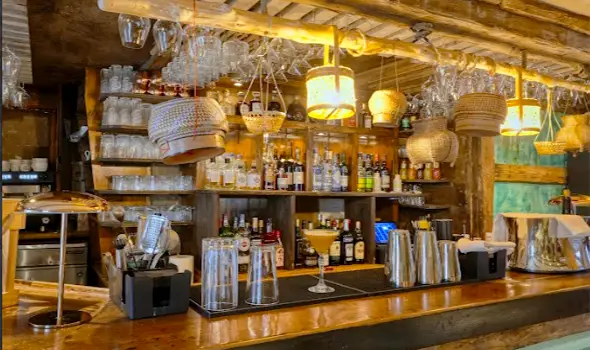 Теплый минималистичный интерьер бара ресторана Pom Thai в Куршевеле с плетеными лампами и деревянной отделкой.