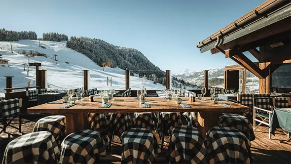 Солнечная терраса ресторана Le Relais des Fermes с видом на горы.