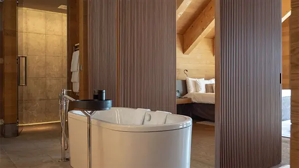 Интерьер ванной комнаты и спальни в сьюте The Chedi Andermatt в альпийском стиле.