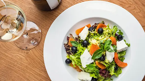 Fresh summer salad with cheese and white wine.