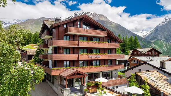 Exterior of the wooden hotel against mountains.
