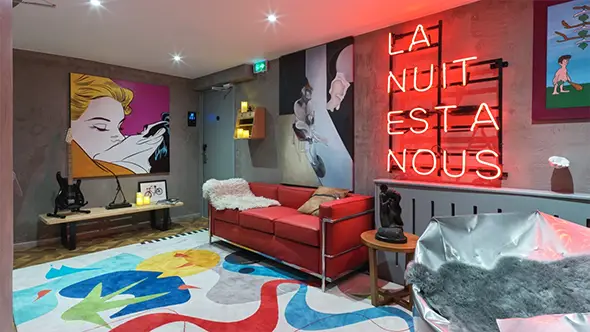 Interior with a red sofa, neon sign, and pop art paintings.