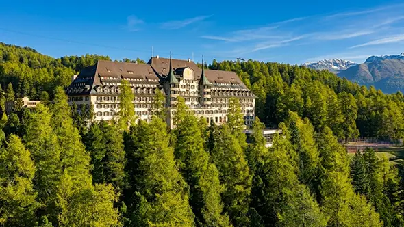 Внешний вид отеля Suvretta House в Санкт-Морице, окруженного лесом.