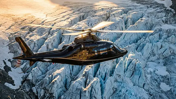 Вертолет AW109 VIP летит над альпийским ледником в Санкт-Мориц.