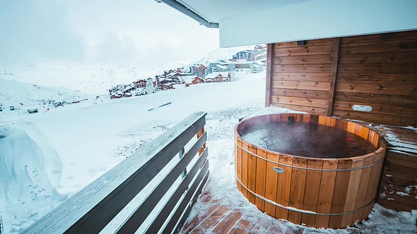 Steaming Nordic bath on an open balcony above the snow-covered rooftops of Val Thorens