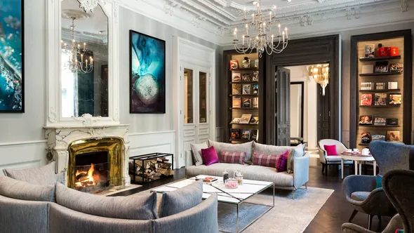 Салон с мраморным камином, серыми диванами и книжными полками, Hôtel Mont-Blanc в Шамони