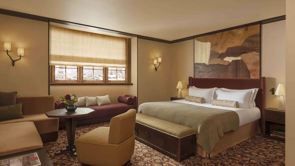 Bedroom with marquetry panel above a velvet bed and a window over the village at Le Saint Roch Courchevel