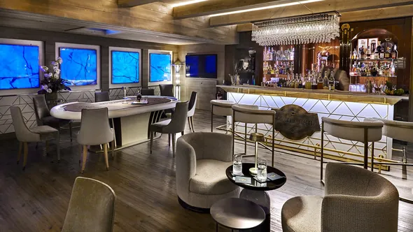 Prohibition Bar with a large oval table, armchairs and a backlit counter at Lys Martagon, Courchevel 1850