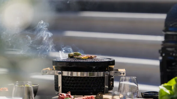 Гриль Yakiniku дымится на столе террасы над склонами Куршевеля в обеденное время