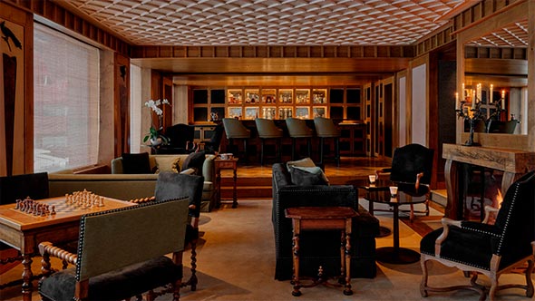 Уютная гостиная с камином и баром в отеле Aman Le M&eacute;l&eacute;zin для вечернего отдыха. / Cozy lounge with a fireplace and bar at Aman Le M&eacute;l&eacute;zin hotel for evening relaxation.