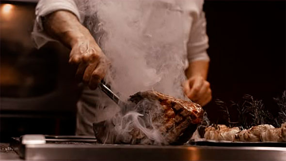Шеф-повар ресторана Django в Куршевеле 1850 готовит филе говядины Вагю с дымком для праздничного меню. / Chef at Django restaurant in Courchevel 1850 preparing smoked Wagyu beef fillet for the festive menu.