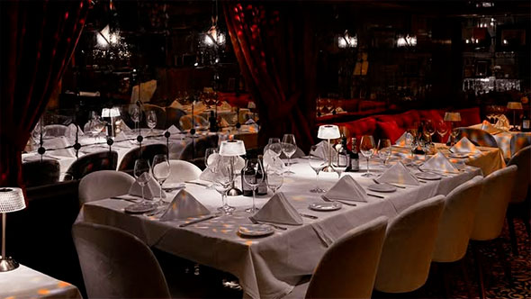 Роскошный интерьер ресторана и пиано-бара Django в Куршевеле 1850 с сервированными столами и атмосферой закрытого клуба. / Luxury interior of Django restaurant and piano bar in Courchevel 1850 featuring elegantly set tables and a private club atmosphere.