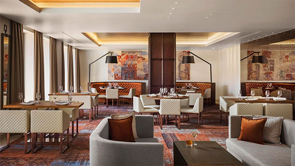 Стильный интерьер ресторана Steak House by Viceroy с мягкой мебелью, современными картинами и уютными столиками для вечернего гала-ужина.