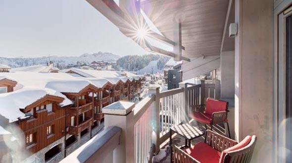 Вид с солнечного балкона номера в отеле Le K2 Djola на заснеженные Альпы и курорт Куршевель 1850. / View from a sunny balcony of a suite at Le K2 Djola hotel overlooking the snowy Alps and Courchevel 1850 resort.