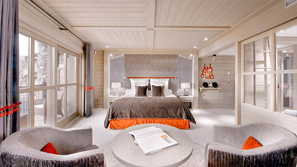 Роскошная спальня в сьюте Le K2 с кроватью King-size, деревянной отделкой, элегантной мебелью и выходом на террасу с видом на горы.