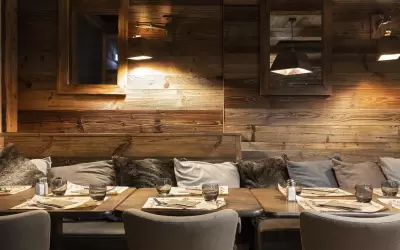 Cosy wooden interior of l Auberge des Balcons restaurant with set tables.