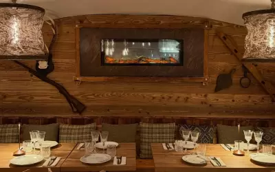 Cosy wooden interior of Chez Augustine restaurant with a fireplace and set tables