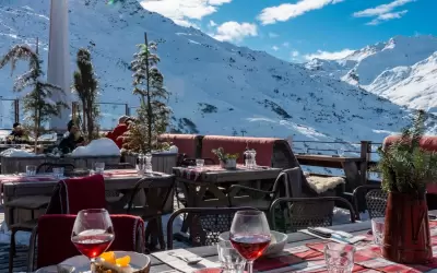 Outdoor terrace of Chez Pepe Nicolas restaurant with set tables against snowy mountains