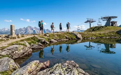 A group of hikers walks near a mountain lake in Val Thorens