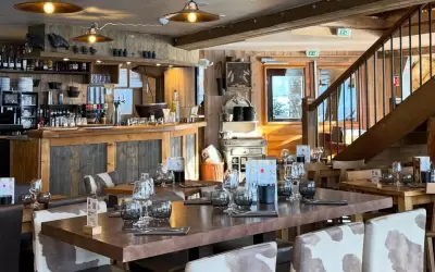 Cosy wooden interior of La Grange restaurant with set tables and a bar counter