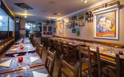 Cosy interior of Le Johns restaurant with set wooden tables and retro posters