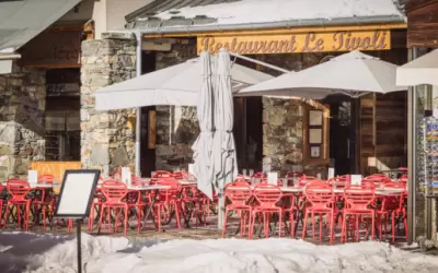 Outdoor terrace of Le Tivoli restaurant with red chairs among snow