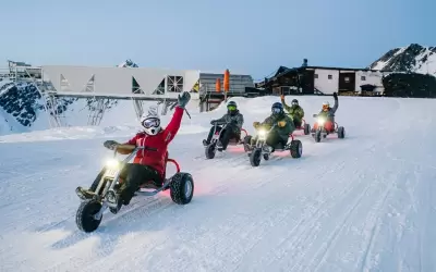 Group of people descending on mountain karts down a snowy slope in Val Thorens.