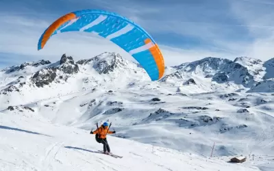 Paraglider taking off on skis from a snowy slope in Val Thorens.