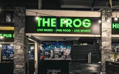 Glowing green sign and entrance to The Frog British pub in Val Thorens