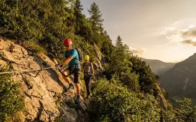 A man and a woman pass a Via Ferrata rock route in the valley