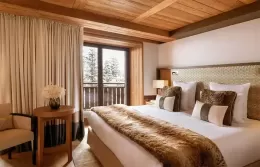 Superior room at Fouquets Courchevel with a bed and winter forest view.