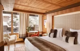 Cozy Junior Suite with a large bed, fur armchair, and panoramic windows.