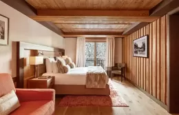 Cozy Junior Suite with a large bed, fur armchair, and panoramic windows.