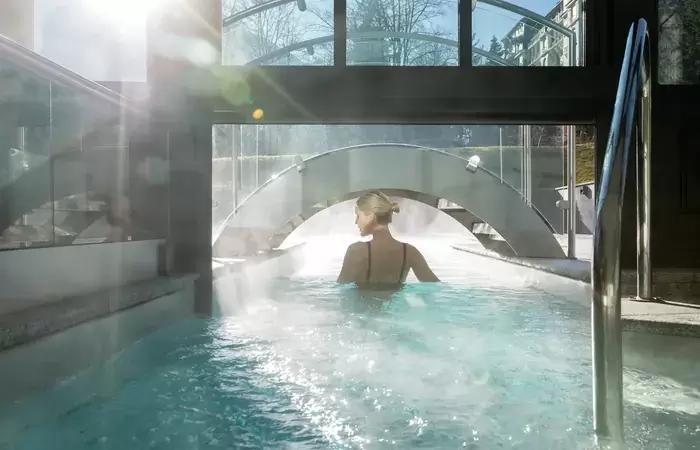Guest swimming beneath a glass arch in the steaming pool at Hotel Mont-Blanc Chamonix
