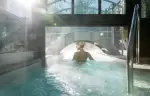 Guest swimming beneath a glass arch in the steaming pool at Hotel Mont-Blanc Chamonix