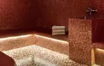 Hammam lined with red and gold mosaic and softly lit benches, Spa by Clarins at Hotel Mont-Blanc Chamonix