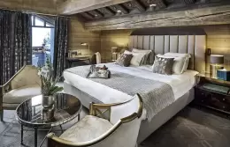 Deluxe Room 3 bed, round table and armchairs under timber beams, Lys Martagon, Courchevel 1850