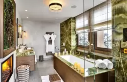Deluxe Room 4 bathroom in green stone with a bathtub and the fireplace, Lys Martagon, Courchevel 1850