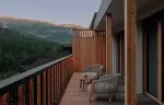 Room balcony with chairs and mountain views.