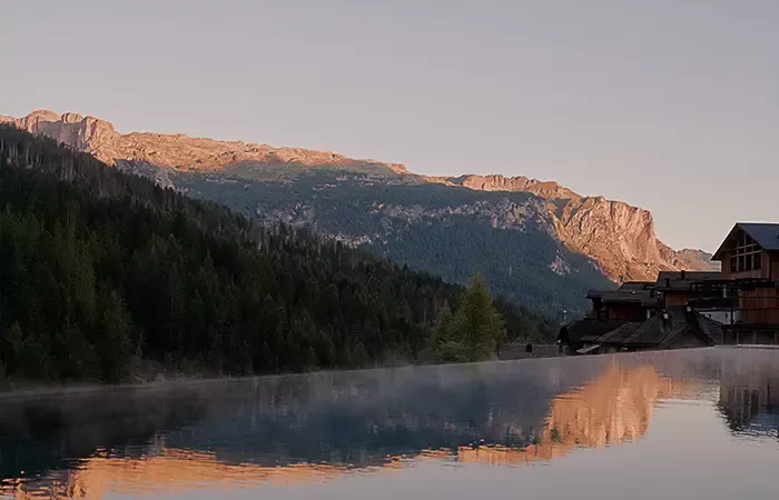 Hotel outdoor pool reflecting mountains at sunset.