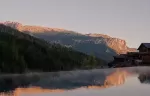 Hotel outdoor pool reflecting mountains at sunset.