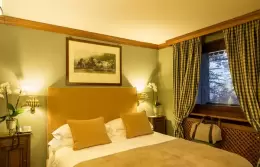 A Deluxe Room with a yellow headboard and checked curtains, Hotel Hermitage, Breuil-Cervinia