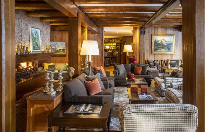 The wood-panelled lounge with a fireplace at Hotel Hermitage, Breuil-Cervinia