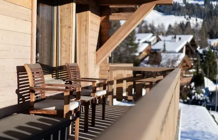 A balcony with chairs overlooking the snowy village chalets at No. 14 Verbier