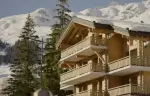 The chalet facade with wooden balconies under snow at No. 14 Verbier