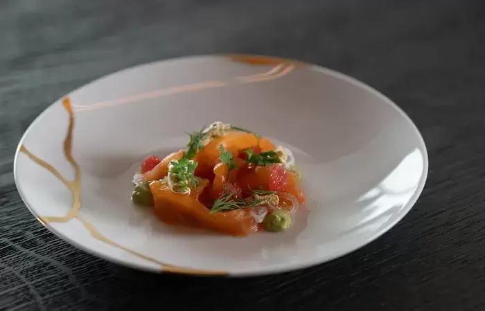A plated fish starter garnished with fresh herbs at No. 14 Verbier