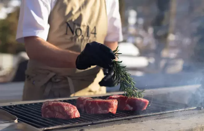 Steaks on an outdoor grill with a sprig of rosemary at No. 14 Verbier